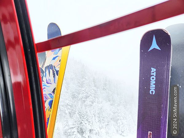 Looking out a gondola cabin at snowy trees